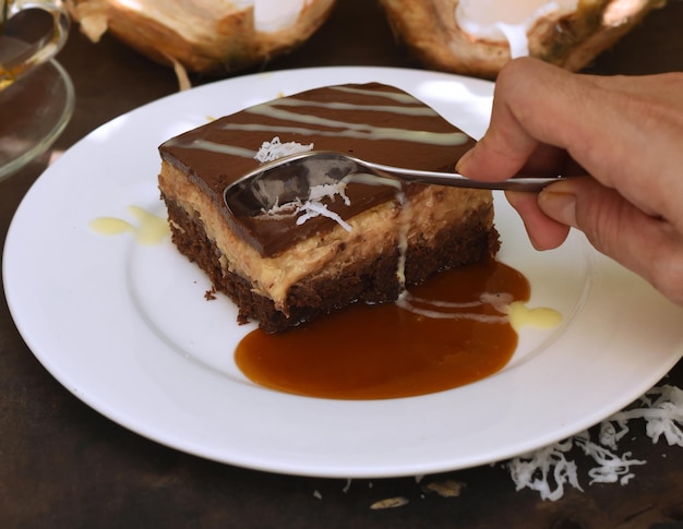 Cuchara de mano tomando un trozo de pastel de coco