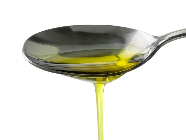 Foto cuchara de metal vertiendo aceite de oliva de cerca sobre fondo blanco.