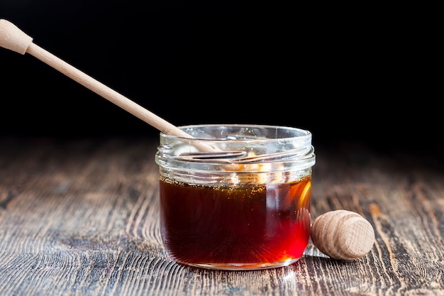 Una cuchara para miel junto con miel de abeja de alta calidad, una mesa vieja en la que hay una miel de abeja dulce y saludable y una cuchara especial de madera.