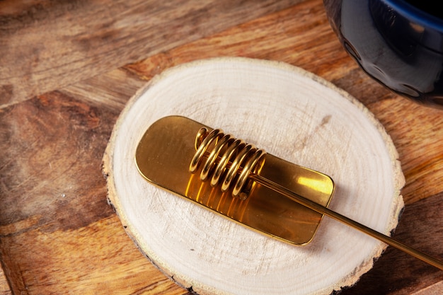 Cuchara de miel de oro en tablón de madera de cerca. Utensilio de cocina