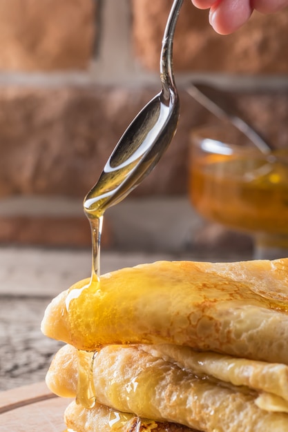 Cuchara de miel que fluye en la pila de panqueques Comida concepto vacaciones Shrovetide Maslenitsa