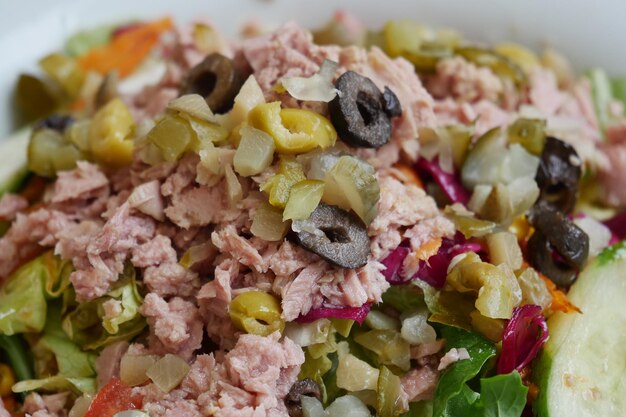 Cuchara recoger ensalada de atún de un tazón en la mesa