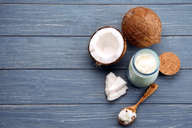 Cuchara y tarro de cristal con aceite de coco fresco sobre fondo de madera