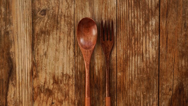 Foto cuchara y tenedor de madera sobre fondo de madera. electrodomésticos de madera de estilo asiático. copia espacio