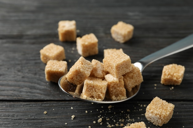 Cuchara con terrones de azúcar sobre fondo de madera, de cerca