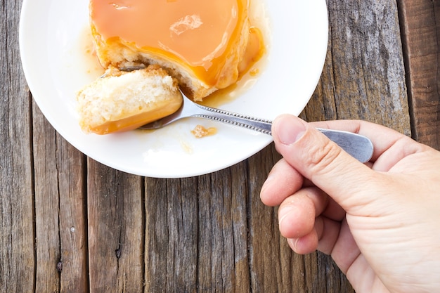 Cuchara del uso de la mujer que escoge la torta de las natillas sobre la tabla de madera.