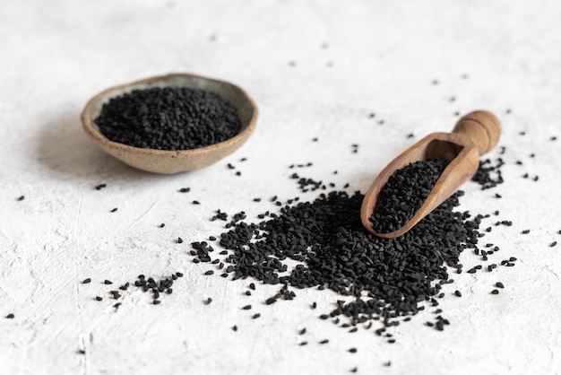 Cucharada de especias indias Comino negro nigella sativa o semillas de kalonji en la mesa blanca de cerca