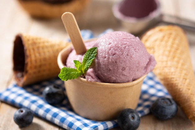 Cucharadas de helado de arándanos con waffle sobre mesa de madera