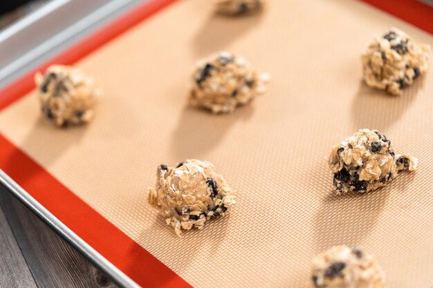 Cucharadas de masa para galletas en un caramelo para hornear para hornear galletas masticables de avena con pasas.