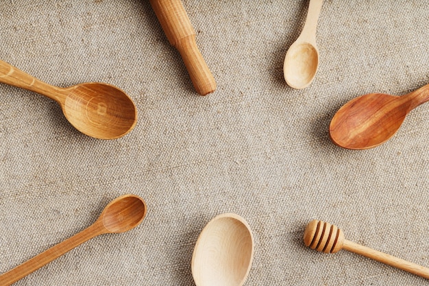 Cucharas artesanales hechas de diferentes tipos de madera se encuentran en una fila sobre una tela de arpillera de cáñamo