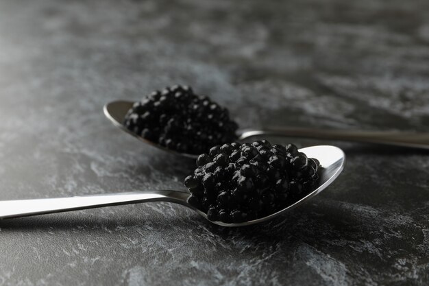 Cucharas con caviar negro sobre fondo negro ahumado