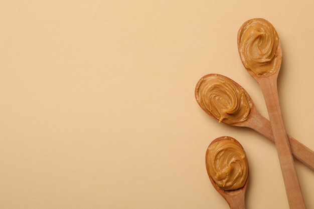 Cucharas de madera con mantequilla de maní sobre fondo beige