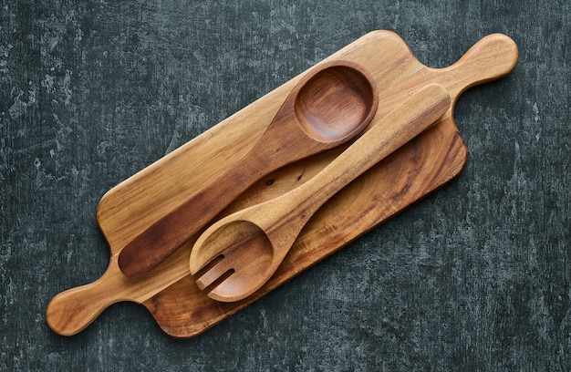 Cucharas de madera en la tabla de cortar de madera sobre fondo gris