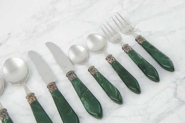Cucharas, tenedores y cuchillos sobre fondo gris blanco.
