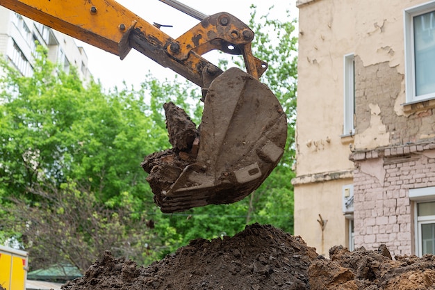 El cucharón de la excavadora vierte el suelo