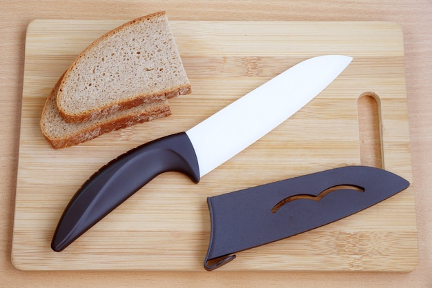 Cuchillo de cerámica con mango negro sobre una tabla de cortar de madera