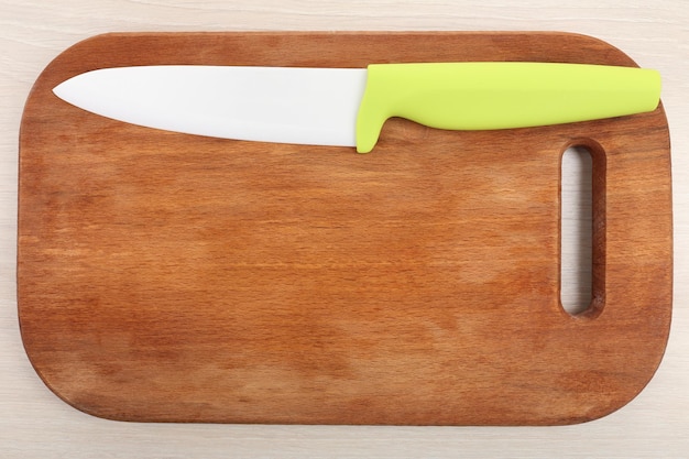 Foto cuchillo de cocina y tabla de cortar sobre mesa de madera