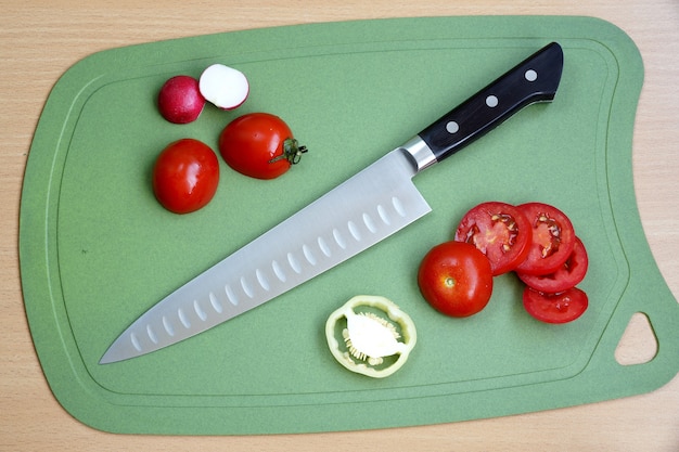 Foto cuchillo cocinero universal con hoja grande sobre tabla de cortar