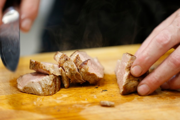 El cuchillo corta la carne caliente cocida. Corta la carne frita. Carne lista. Carne caliente preparada. Carne con humo