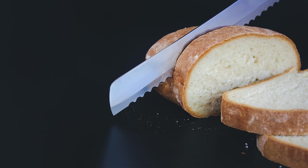 Foto el cuchillo está cortando una hogaza de pan en rebanadas pan de semilla pan casero para cortar pan