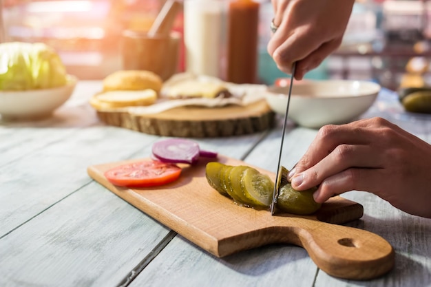 Cuchillo cortando verduras en rodajas de pepino en escabeche en el ingrediente de tablero de madera para ensalada salada