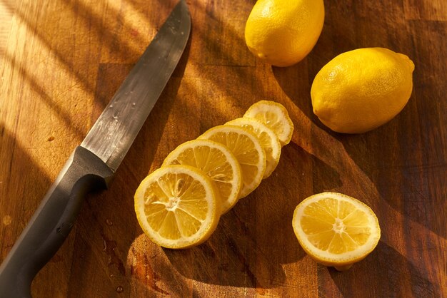 Un cuchillo y un cuchillo están sobre una tabla de cortar de madera con limones.