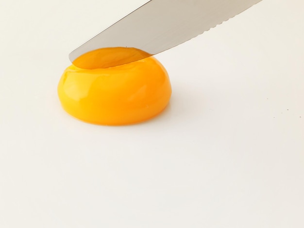Un cuchillo está a punto de cortar un huevo amarillo en un agujero.