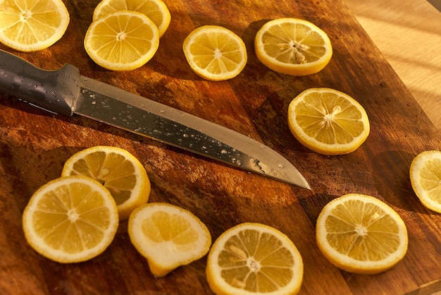 Un cuchillo está en una tabla de cortar con limones.