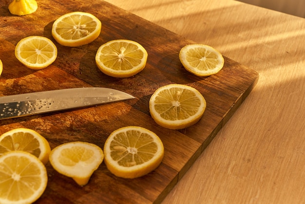 Un cuchillo está en una tabla de cortar con rodajas de limón.