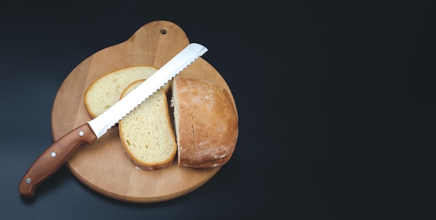 Foto un cuchillo grande corta pedazos delgados de pan blanco de una hogaza rectangular