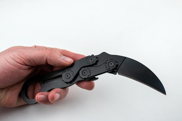 Cuchillo karambit negro en mano sobre fondo blanco aislado