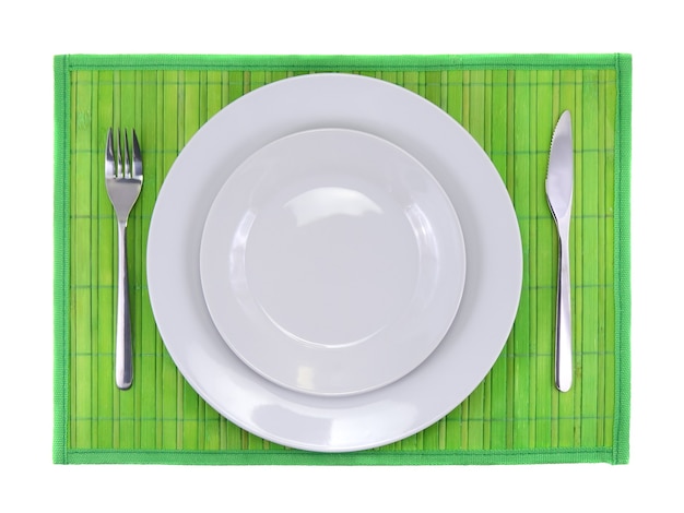 Cuchillo de mesa, plato, tenedor sobre fondo de color verde.