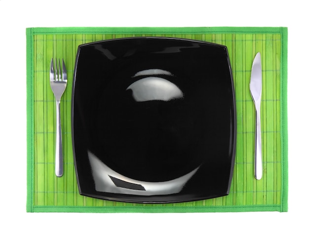 Cuchillo de mesa, plato, tenedor sobre fondo de color verde.