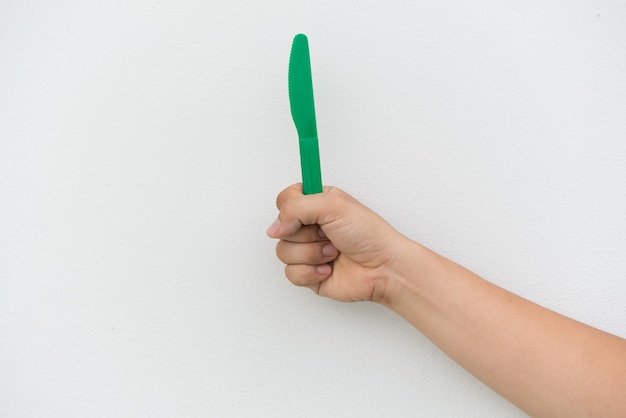 Cuchillo de plástico verde en la mano sobre fondo blanco.