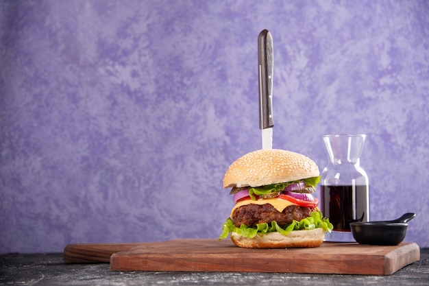 Cuchillo en salsa de tomate salsa de sándwich de carne sabrosa en la tabla de cortar de madera en el lado izquierdo sobre una superficie de hielo aislada con espacio libre