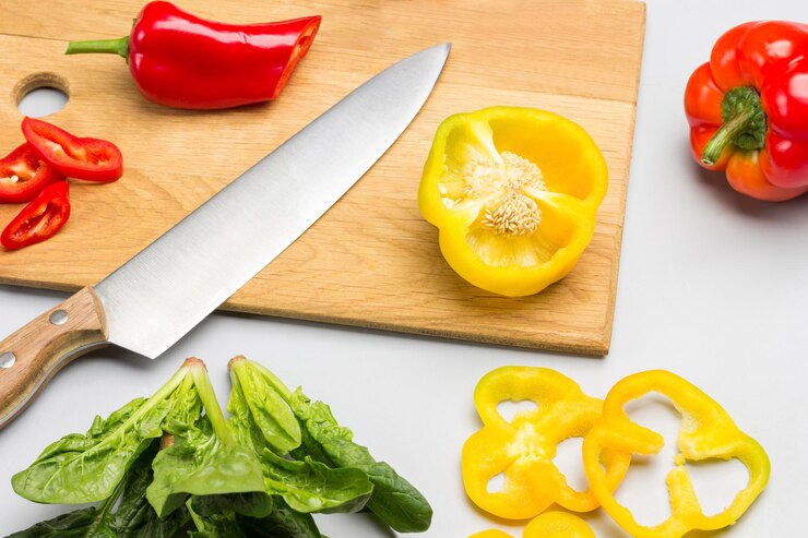 Foto cuchillo en la tabla de cortar rebanadas de pimienta amarilla hojas de espinaca