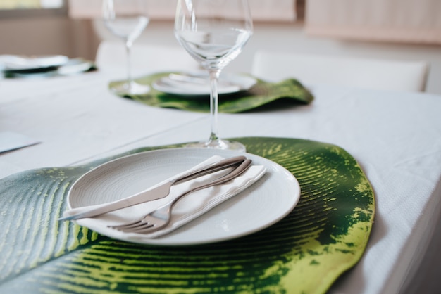 Cuchillo y tenedor colocados sobre una servilleta sobre un plato blanco. Colocado en una sábana para una boda