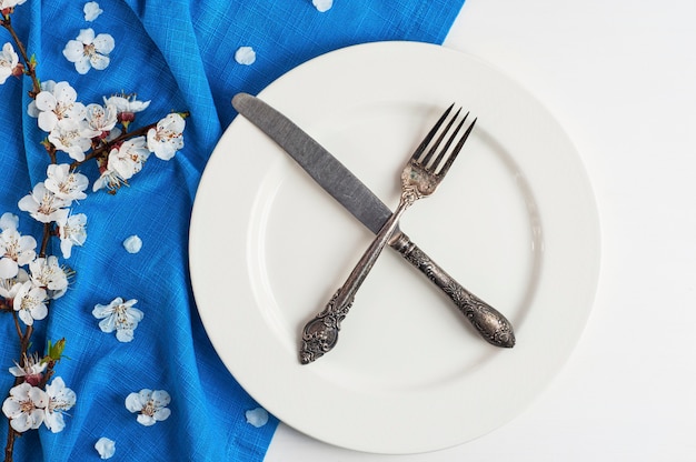 Cuchillo y tenedor cruzados en un plato blanco vacío