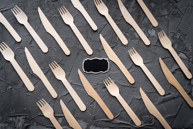 Cuchillo y tenedor de madera sobre fondo negro. Concepto ecológico de cero residuos. Vista superior con espacio para texto. Copia espacio