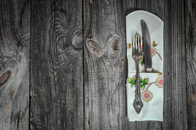 Cuchillo y tenedor de mesa en superficie de madera gris.