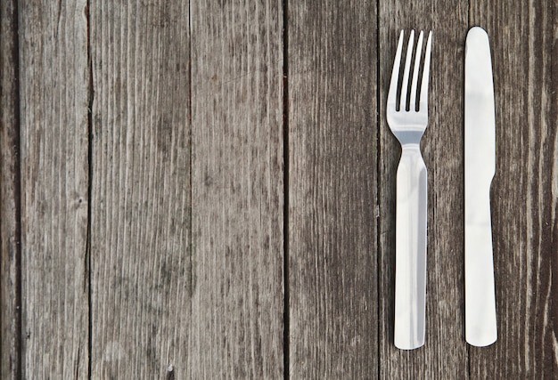 Cuchillo y tenedor sobre la mesa de madera antigua