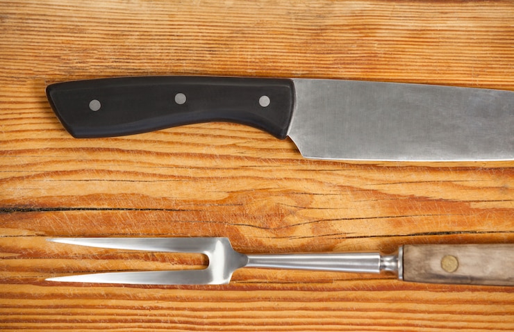 Foto cuchillo y tenedor sobre tabla de madera