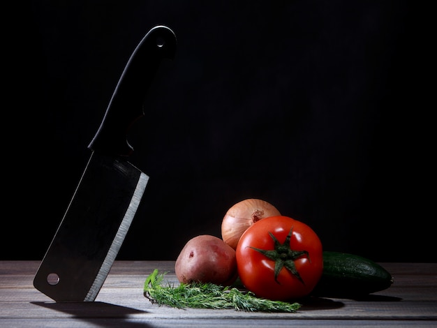 Foto cuchillo y verduras en mesa de madera