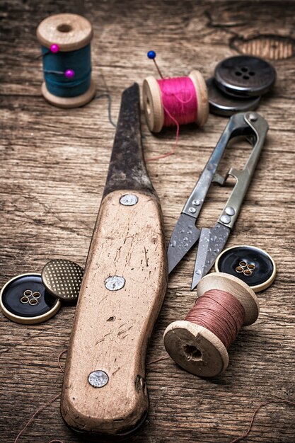 Cuchillo viejo y suministros de costura en el fondo de madera vieja