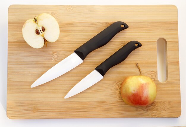 Cuchillos de cerámica con mangos negros sobre una tabla de cortar de madera