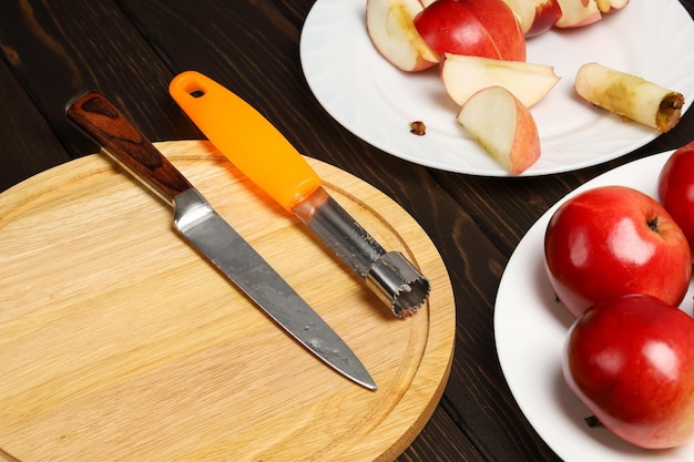 Cuchillos de cocina para cortar y quitar el núcleo de las frutas en la tabla de cortar junto a las manzanas rojas en el plato