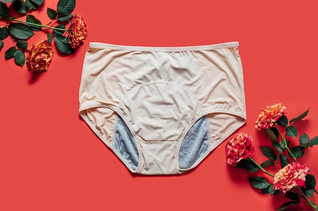 Cuecas menstruais reutilizáveis com flor rosa sobre fundo vermelho Cuecas menstruais absorventes e acessíveis para absorver o fluido menstrual