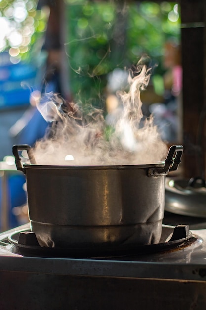 Foto cuece sopa en una olla de metal en una estufa de gas con humo en la cocina tailandesa para hacer comida para el desayuno