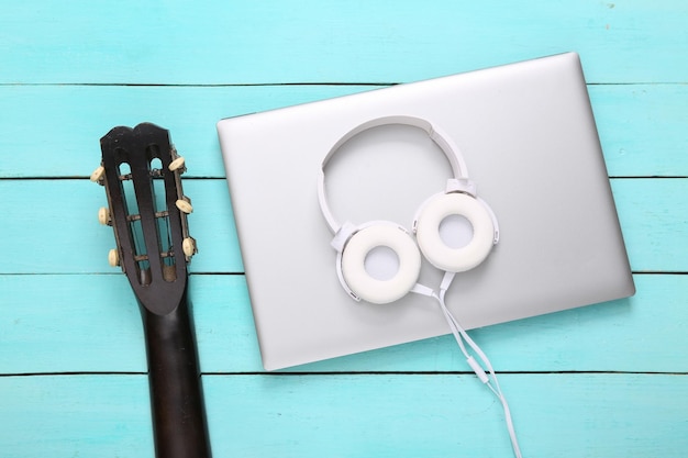 Foto cuello de guitarra acústica y portátil con auriculares sobre fondo de madera azul lecciones de guitarra en línea concepto musical vista superior lay flat