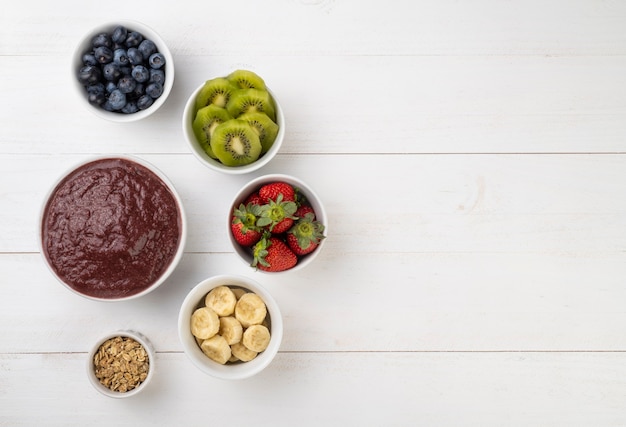 Cuenco de acai típico brasileño con frutas y muesli sobre mesa de madera con espacio de copia.